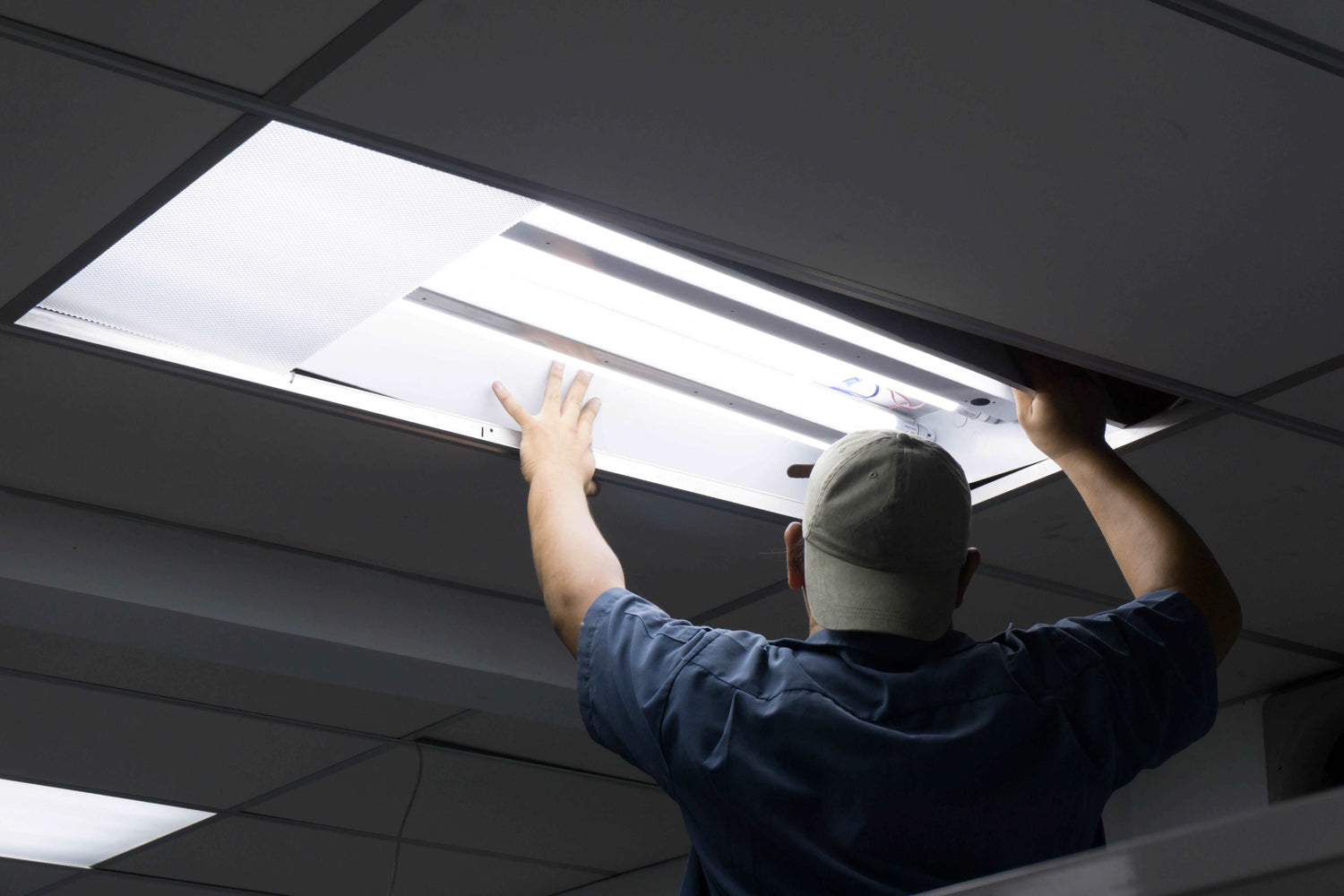 Mann tauscht Leuchtstofflampe durch LED Röhre aus